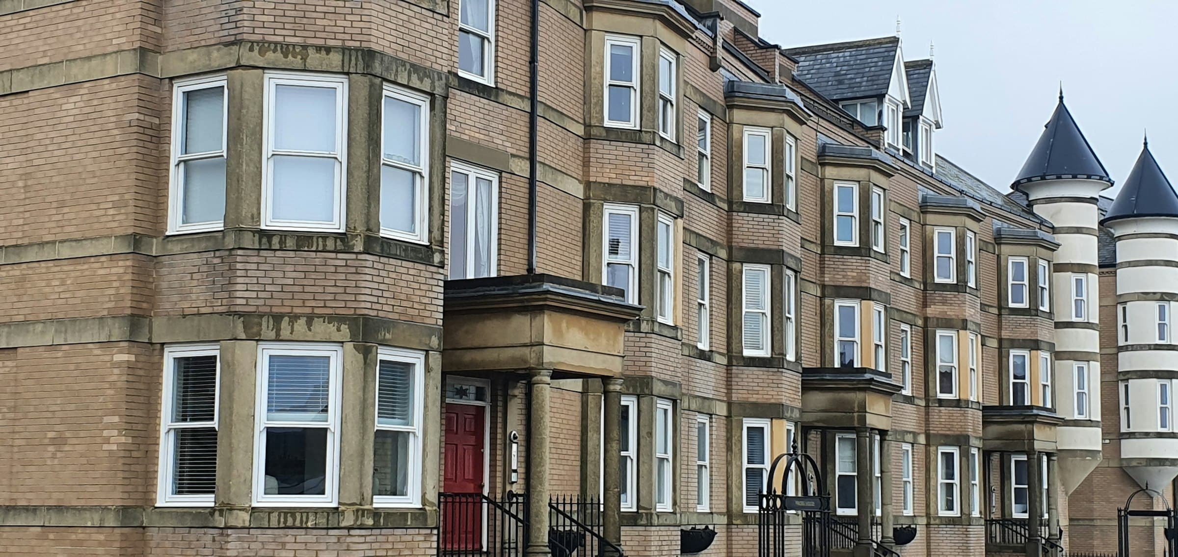 Row of red-brick Victorian terraced houses on a UK residential street